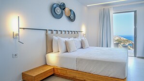 Een moderne slaapkamer met een groot bed, een houten platform, een wandlamp en uitzicht op zee.