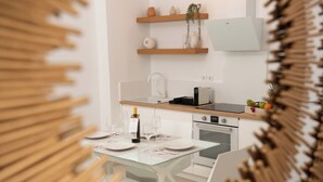 Een moderne keuken met witte kasten, een glazen eettafel en een inbouwoven.