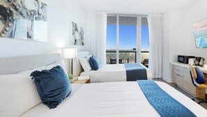 A hotel room with two beds, a desk, a TV, and a large window with a city view.