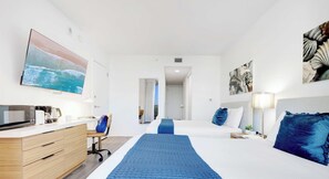Una camera d'albergo con un letto, una scrivania con un computer, una sedia e una televisione.