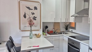 Una cocina moderna con armarios blancos, un lavamanos de acero inoxidable y un horno empotrado.
