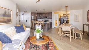 A modern living room with a sofa, coffee table, and dining area. - NEW!  Deluxe Ski In/Out 2B/2B condo at Solitude (Brighton)