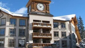 A multi-story building with a prominent clock tower, balconies, and snow on the roof. - NEW!  Deluxe Ski In/Out 2B/2B condo at Solitude (Brighton)