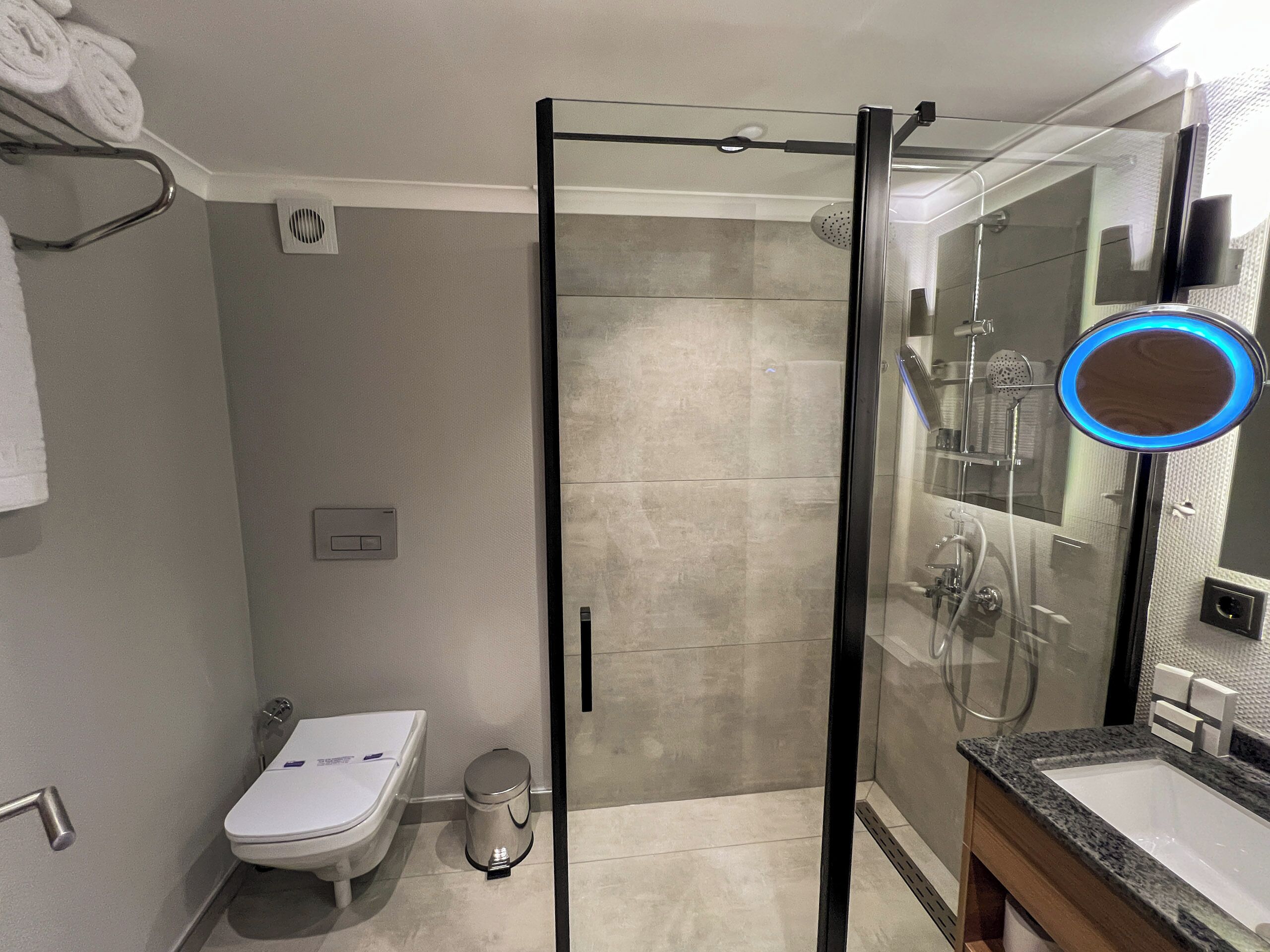 Un baño moderno con ducha de vidrio, inodoro y lavamanos con encimera de granito.