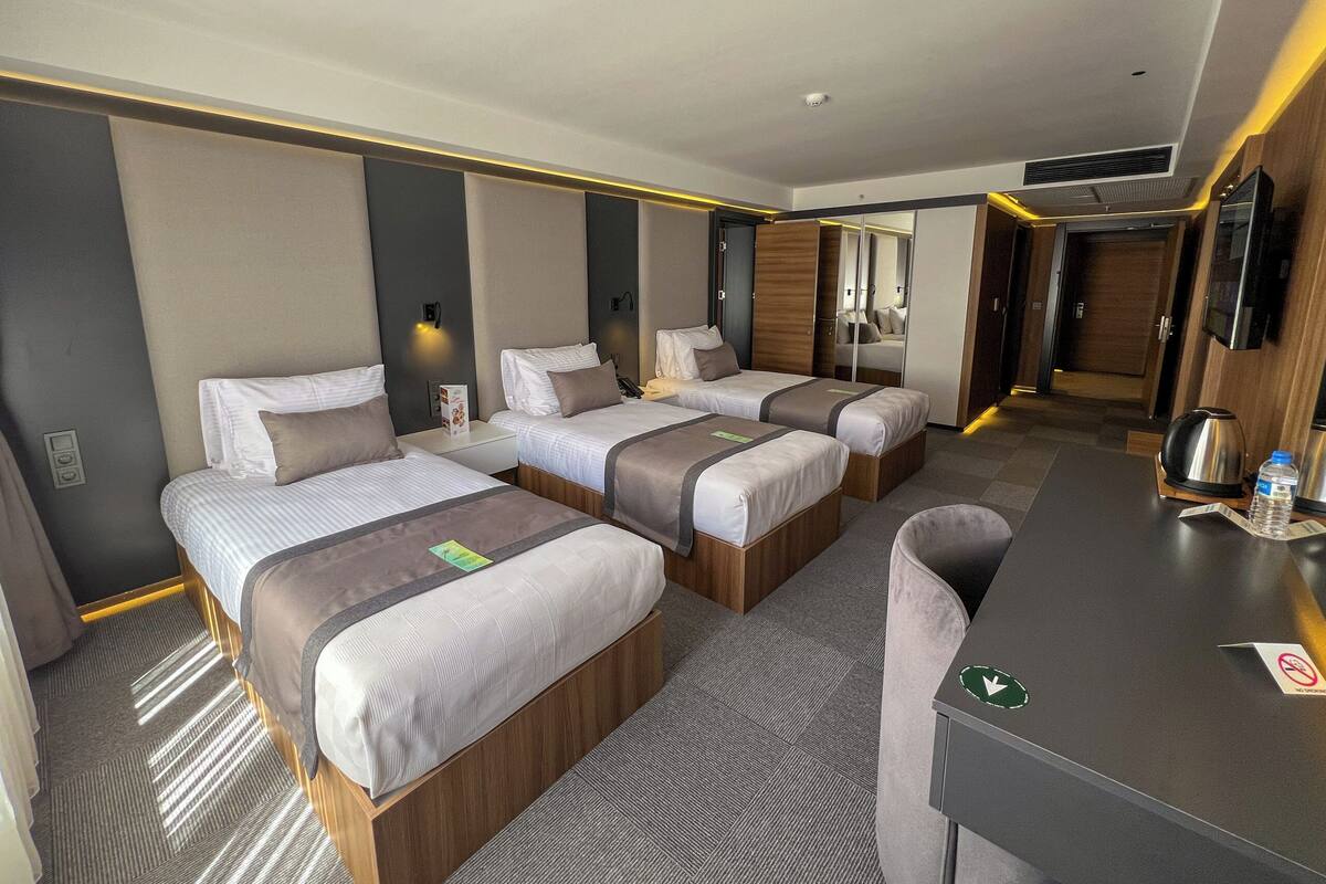 A hotel room with two beds, a desk, and a mirror.