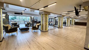A spacious room with wooden flooring, ornate black armchairs, and a large window offering a view of trees and a fence. - Sera Lake Center Hotel (Akçaabat)