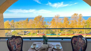 A balcony with a table set for two, overlooking a scenic view of the ocean and autumn trees. - Sera Lake Center Hotel (Akçaabat)