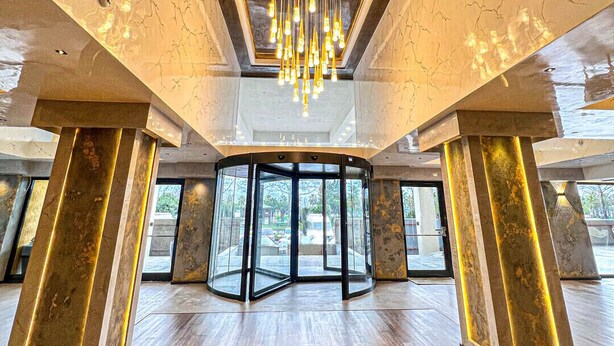 A spacious lobby with a modern chandelier, marble walls, and a revolving door. - Sera Lake Center Hotel (Akçaabat)