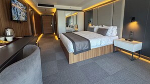 A modern hotel room with a large bed, bedside tables, a desk with a chair, a television, and a mirror. - Sera Lake Center Hotel (Akçaabat)