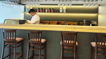 A bar area with wooden chairs, a counter, and hanging wine glasses.