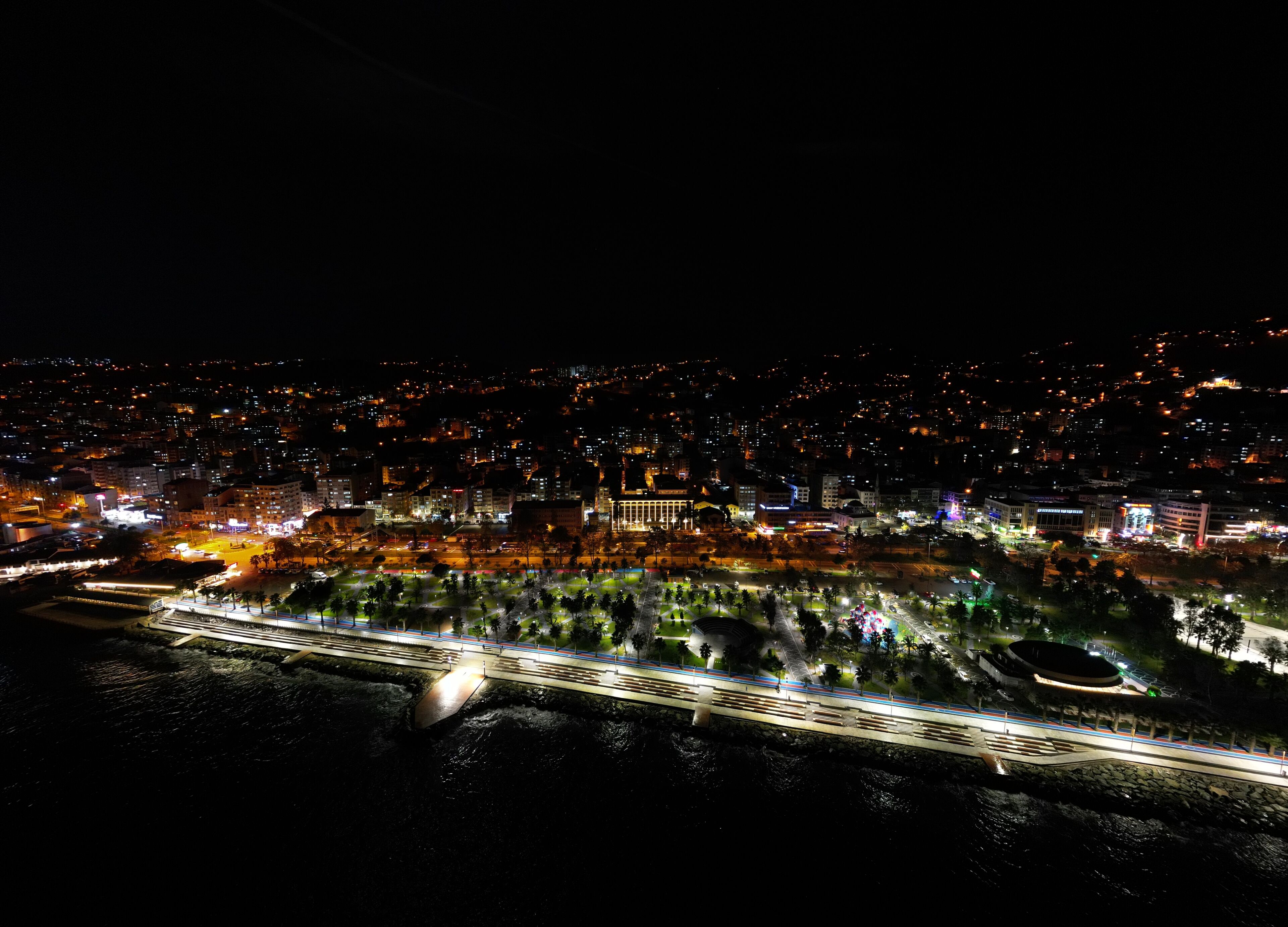 Un paisaje urbano nocturno con un puente destacado y edificios iluminados.