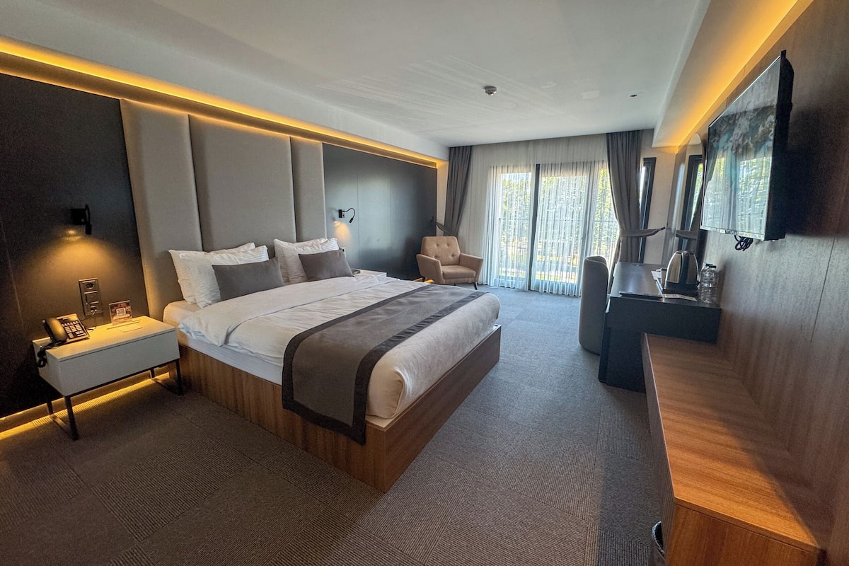 A modern hotel room with a large bed, bedside tables, a desk, and a television.