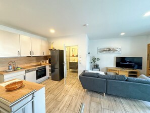 A modern kitchen with white cabinets, a black refrigerator, and a wooden countertop. - Loft Ferienwohnung auf Zwei Ebenen (Gunzenhausen)