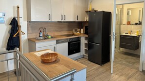 Una cocina moderna con armarios blancos, un refrigerador negro y una encimera de madera.