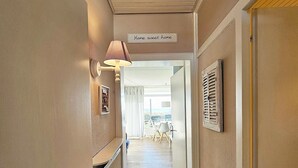 Un couloir avec une pancarte sur laquelle on peut lire « Chez soi, quel bonheur », une lampe et une porte dotée d’une fenêtre.