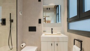 A modern bathroom with a glass shower enclosure, a white toilet, a vanity with a mirror, and a towel rack. - w *| Amazing 1BR at Palacio Real (Madrid)