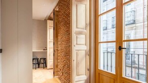 Un corridoio con pavimento in legno, parete in mattoni e un'ampia finestra con balcone.