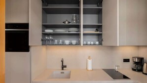Una cucina moderna con mobili bianchi, forno integrato, lavello e macchina per il caffè.