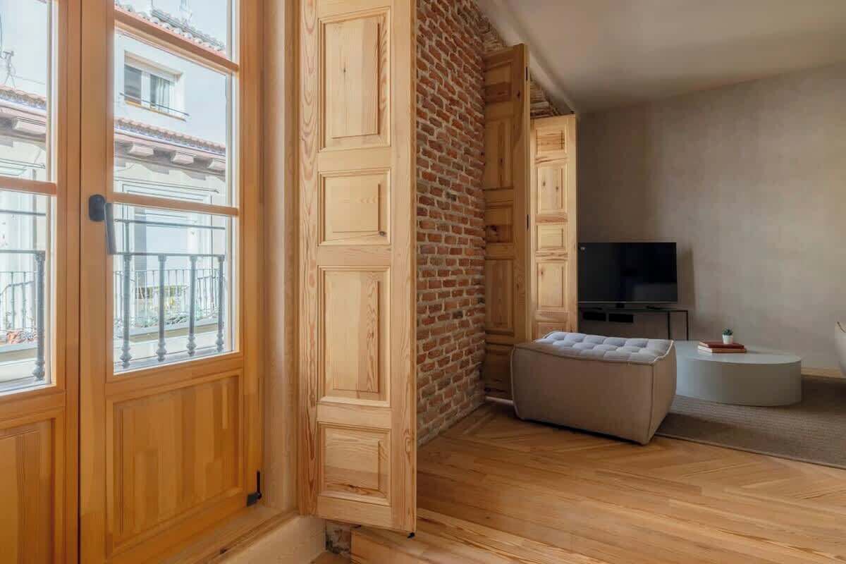 Une pièce avec des lambris en bois, un mur en briques, un téléviseur à écran plat, un banc rembourré et une petite table ronde.