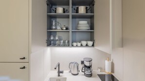 A modern kitchen with a built-in coffee station, including a coffee maker, grinder, and kettle. - Cozy 1BR at Palacio Real (Madrid)