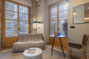A cozy living room with a sofa, a round coffee table, a small table with drinks, and a chair. - Cozy 1BR at Palacio Real (Madrid)
