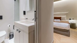 A modern bathroom with a white sink, mirror, and cabinet. - Cozy 1BR at Palacio Real (Madrid)