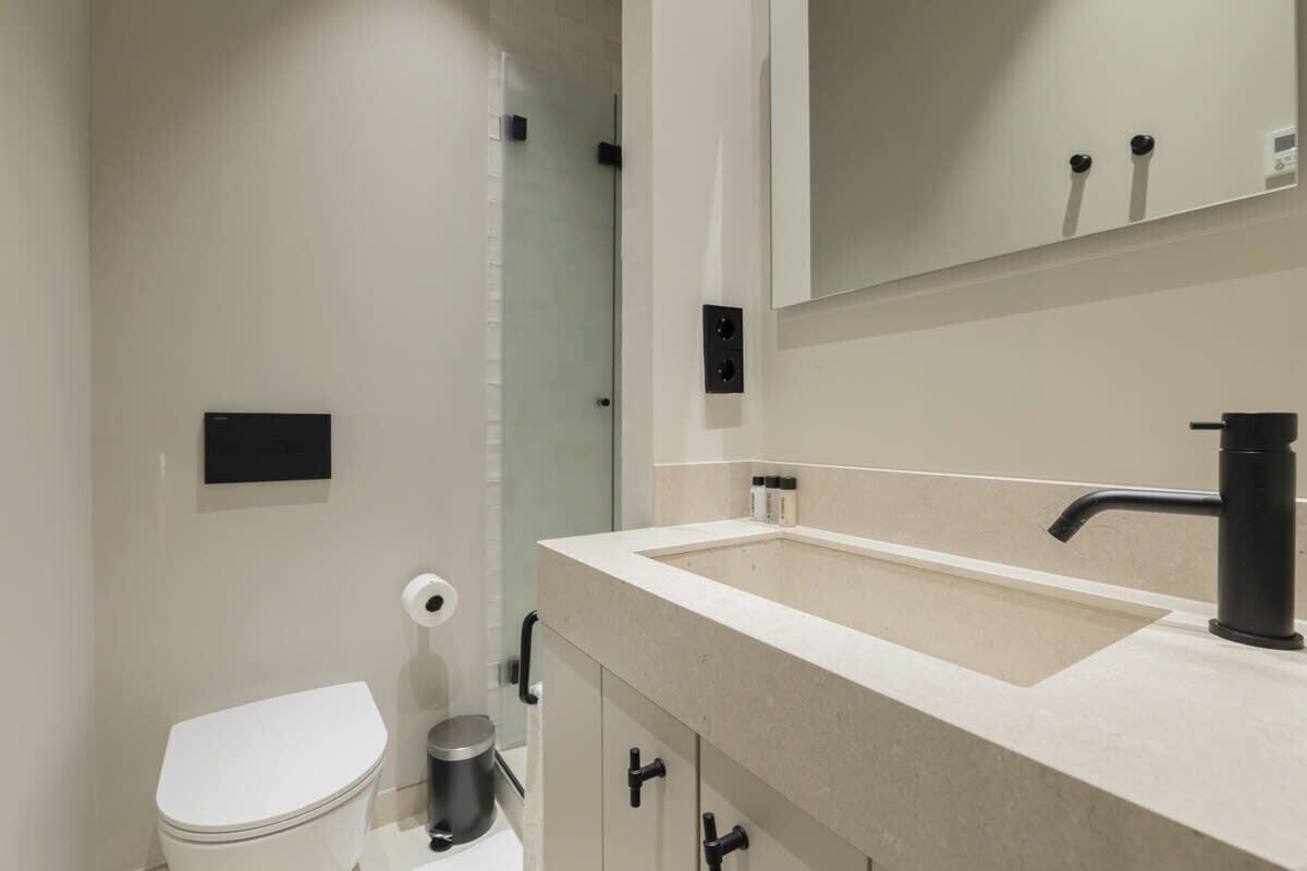 Ein modernes Badezimmer mit Toilette, Waschbecken und Spiegel.