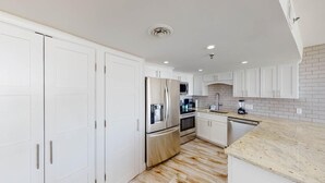 Eine moderne Küche mit weißen Schränken, Edelstahlgeräten und einer Arbeitsplatte aus Granit.