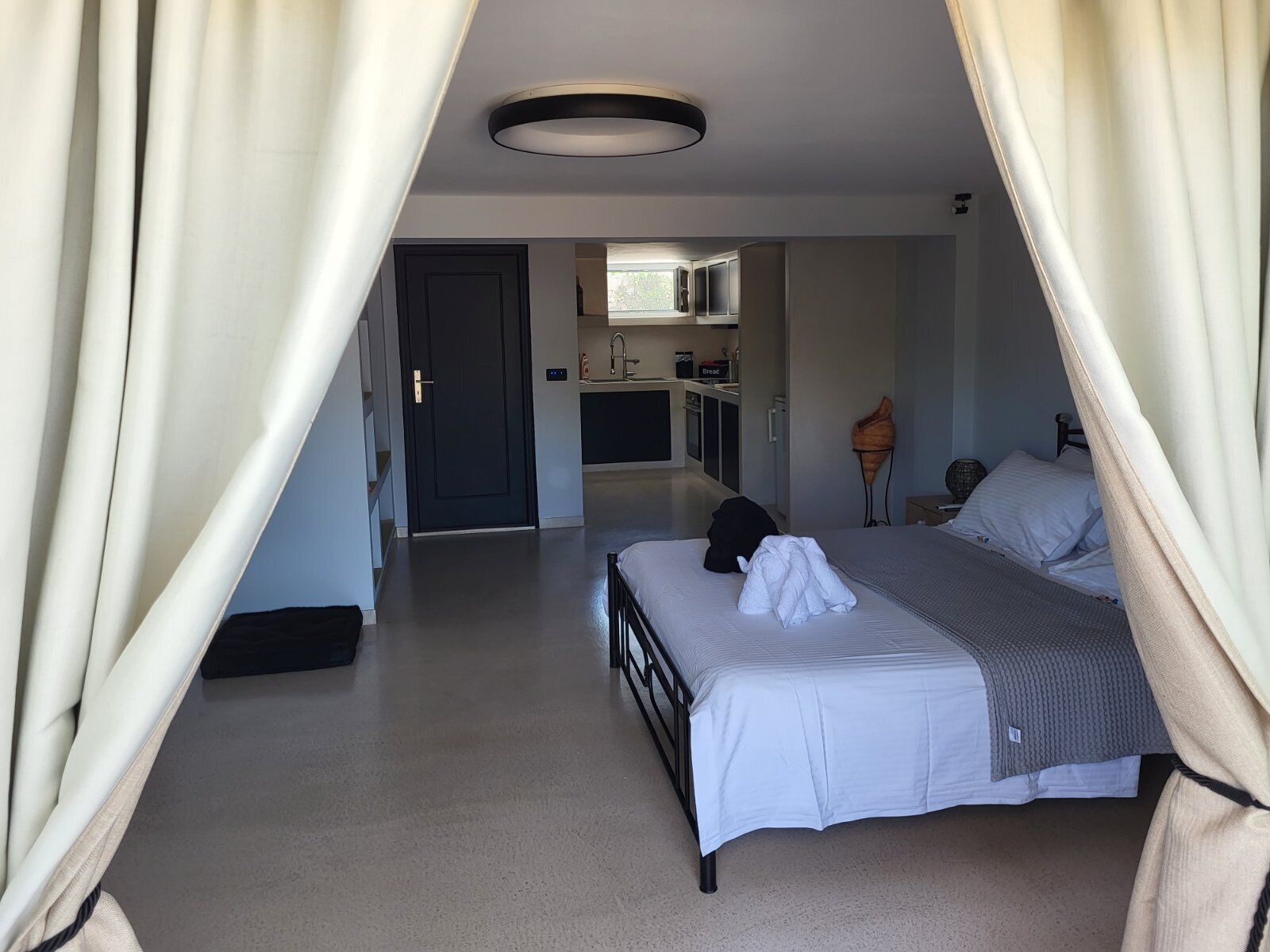 Un dormitorio con cama, mesita de noche y ventana con cortinas.