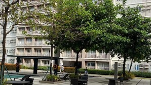 Un patio con mobiliario exterior, una piscina y un edificio con balcones al fondo.