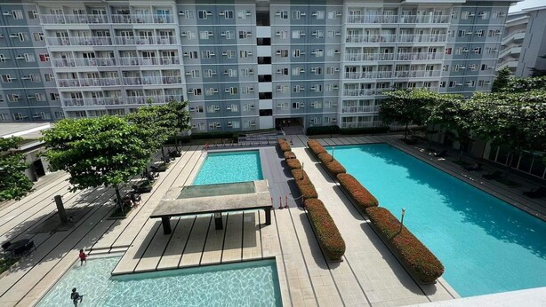 Un moderno edificio de apartamentos con piscina en la azotea, que cuenta con dos piscinas y una zona de estar techada.