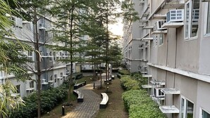 Un edificio residencial con un sendero curvo, vegetación y zonas de estar al aire libre.