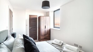 Une chambre moderne avec un lit, une armoire, une fenêtre et un luminaire suspendu.