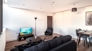 Un salon moderne comprenant un téléviseur à écran plat, un lampadaire, une table à manger avec des chaises et un canapé.