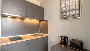 A compact kitchen with grey cabinets, a wooden countertop, a sink, a kettle, and a toaster. - Convenient Budget Sunderland Studio with Views (Sunderland)