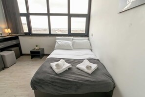 Escritorio, tabla de planchar con plancha y ropa de cama 