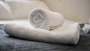 A neatly folded white towel on a dark surface, likely a bed or couch, with a blurred background suggesting a hotel room setting. - Convenient Budget Sunderland Studio with Views (Sunderland)