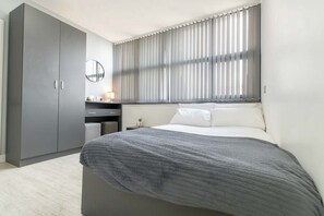 Escritorio, tabla de planchar con plancha y ropa de cama 