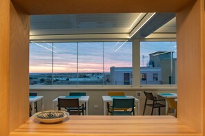 A modern office space with large windows offering a view of the cityscape during sunset. - azzurra guest house  (Lampedusa)