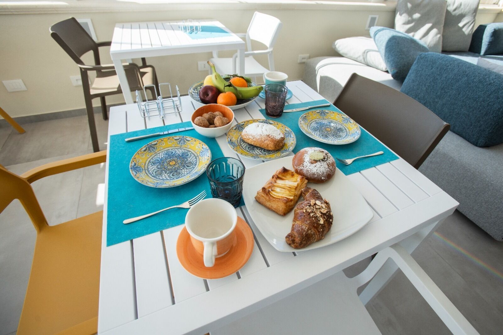 A dining table with plates, cutlery, a bowl of nuts, a glass of water, and pastries.