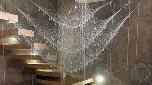 A modern staircase with wooden steps and a net-like structure hanging from the ceiling.