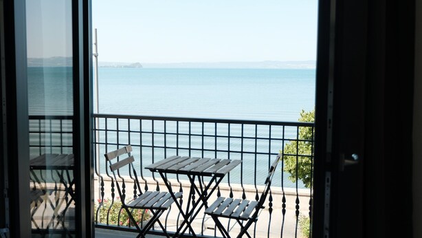 Un balcon avec une table et des chaises donnant sur une mer calme.