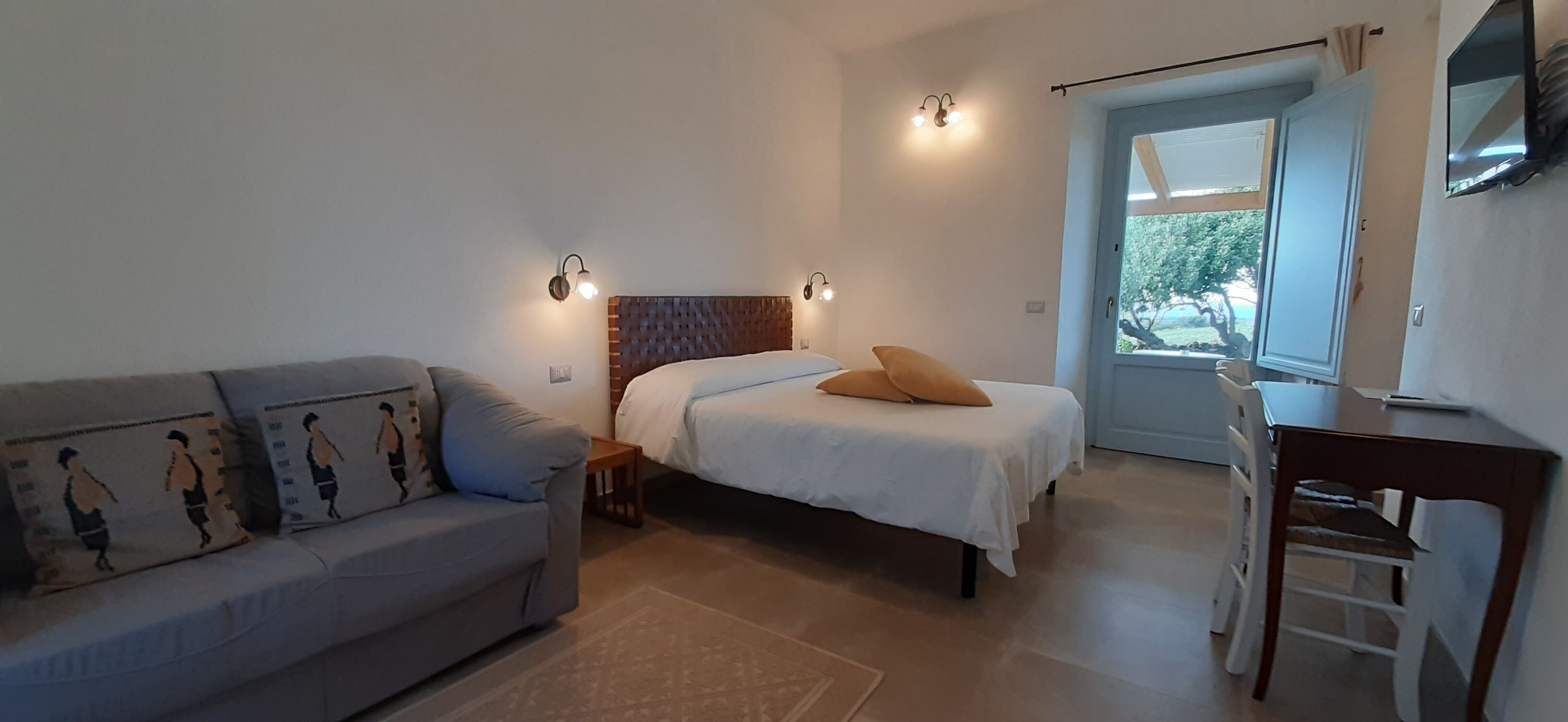 Un dormitorio con cama, sofá, escritorio y silla.