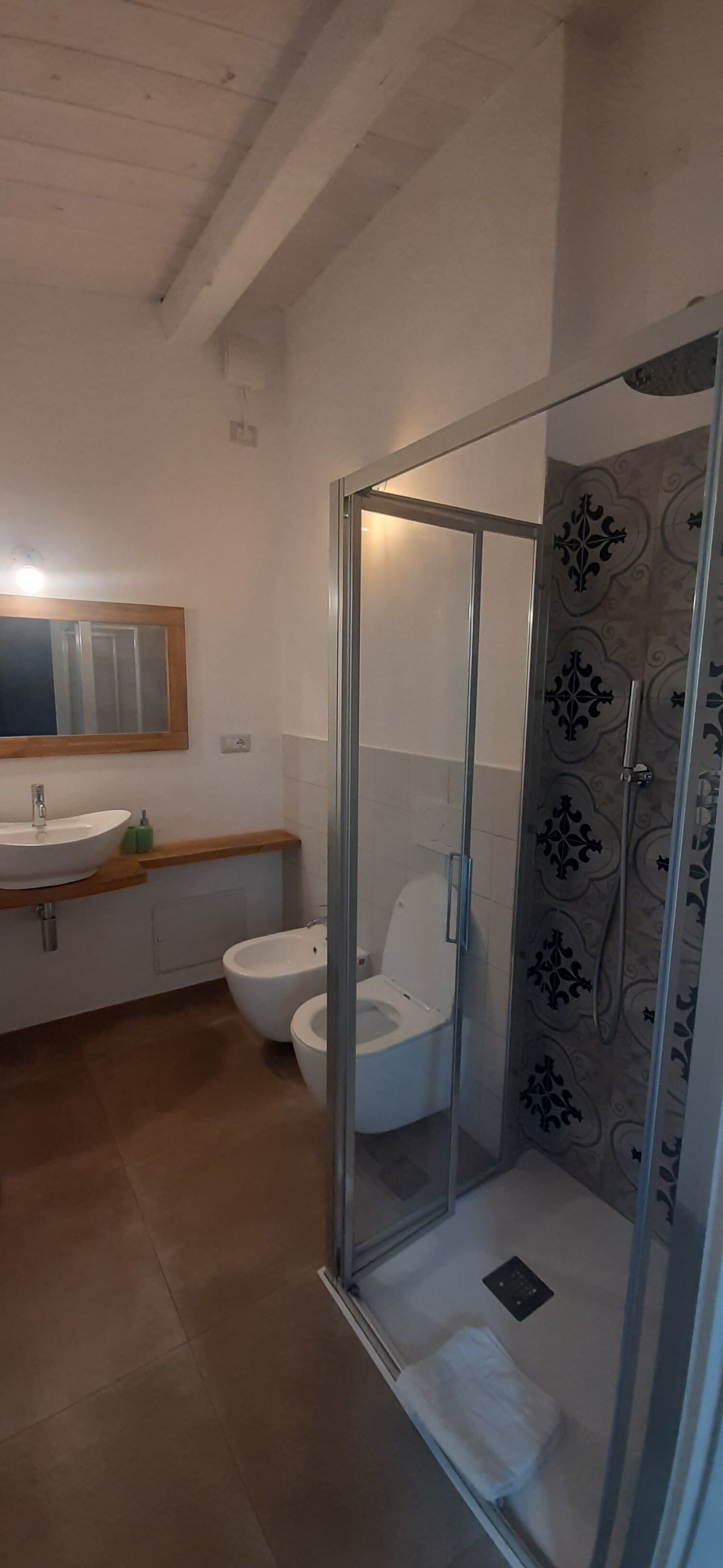 A bathroom with a glass-enclosed shower, a toilet, and a sink with a wooden countertop.