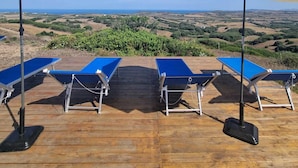 A deck with blue lounge chairs and white umbrellas, overlooking a scenic landscape. - Lispusada B&B (Sassari)