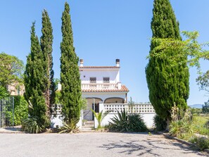 Una casa de dos pisos con techo de tejas, un balcón y un acceso con reja.