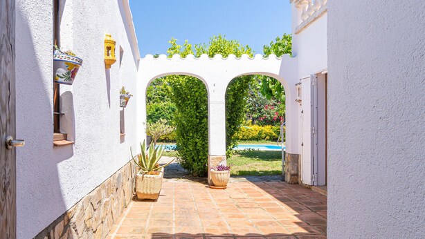 A narrow courtyard with white walls, a tiled floor, and an archway leading to a garden. - "Holiday Home for 6 with Pool, BBQ, Wifi, Near Beach - Sant Pere Pescador, Costa Brava" (Sant Pere Pescador)