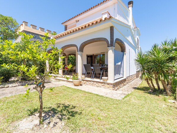 A two-story house with a patio, outdoor seating, and a garden.