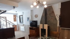 Ein modernes Wohnzimmer mit einem Glastisch, Holzstühlen, einem Fernseher und einem Kamin.