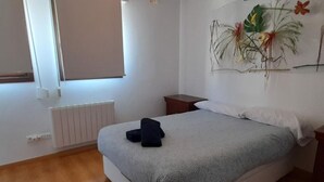 Ein Schlafzimmer mit Bett, Nachttisch, Heizkörper und Fenster.